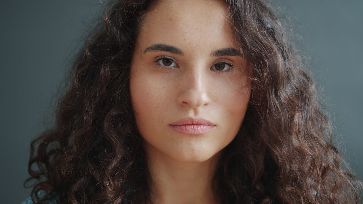 A young woman with curly hair looks forward