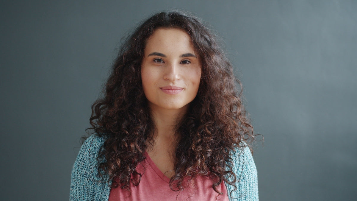 A young woman with curly hair smiles.