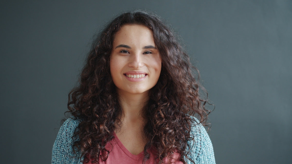 Young woman with curly hair smiles confidently smiling